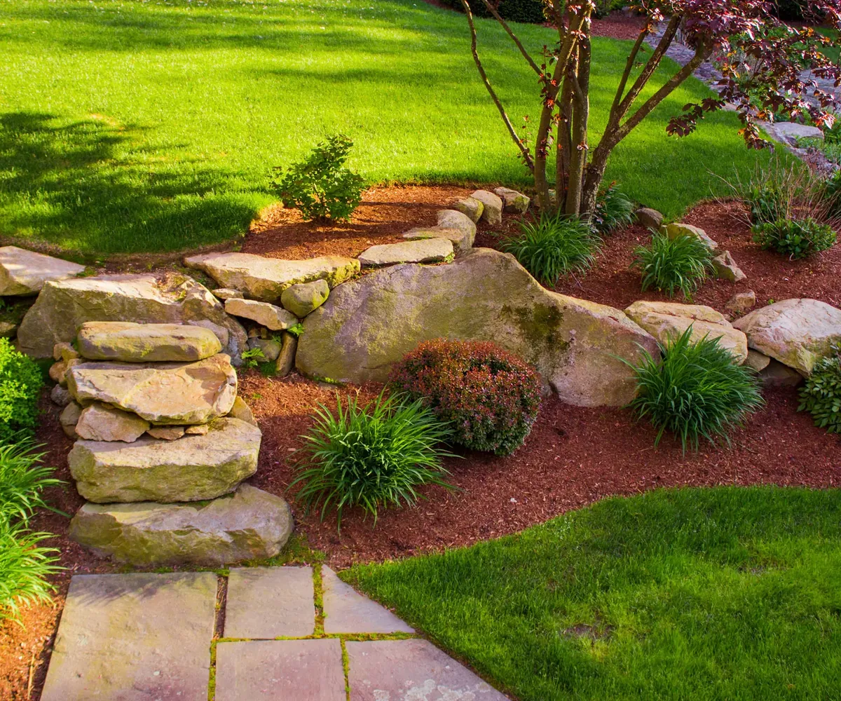 Landscaped front yard with boulder retaining wall and planting beds in Evansville, IN